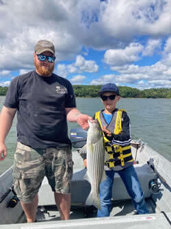 Man and boy holding a Stripped Bass they he caught with Six Fins Guide Service.